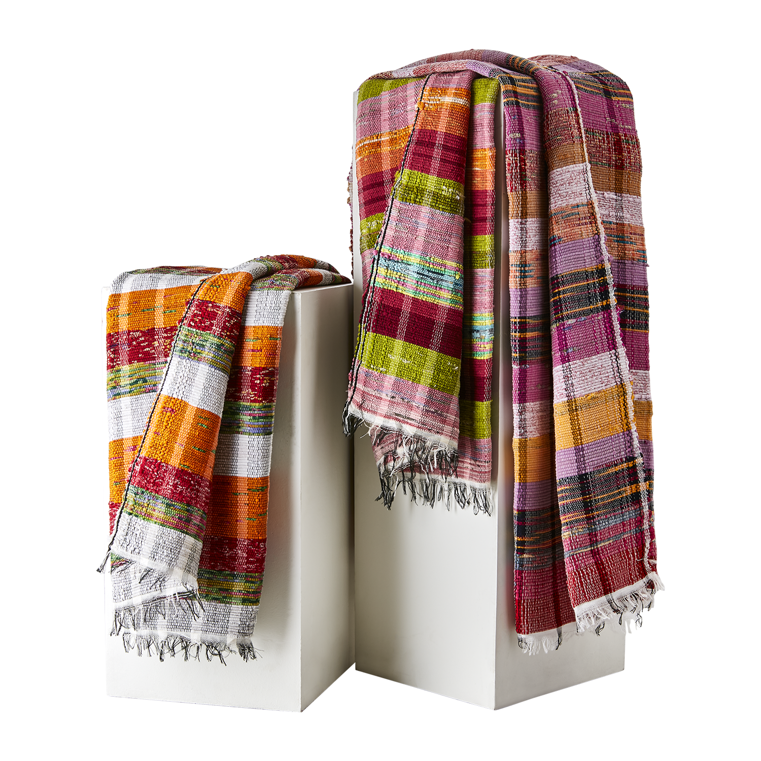 Flerfärgade SOLVEIG picknickfiltar i bomull draperade över vita podier