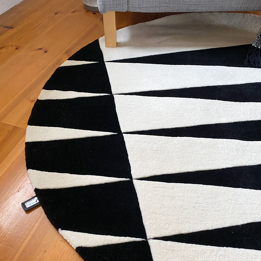 Närbild på handtufftad ullmatta på ett ljust trägolv i en stuga