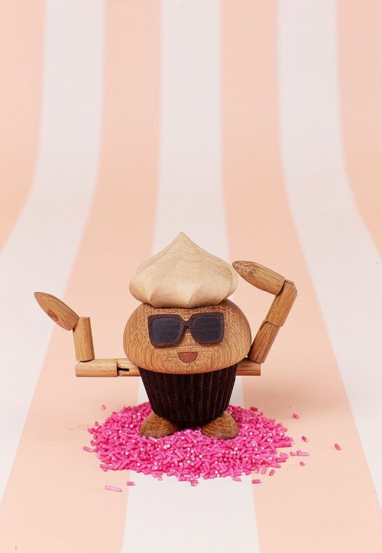 Lekfull träfigur Carrie Cupcake på rosa strössel i ett sommarställe