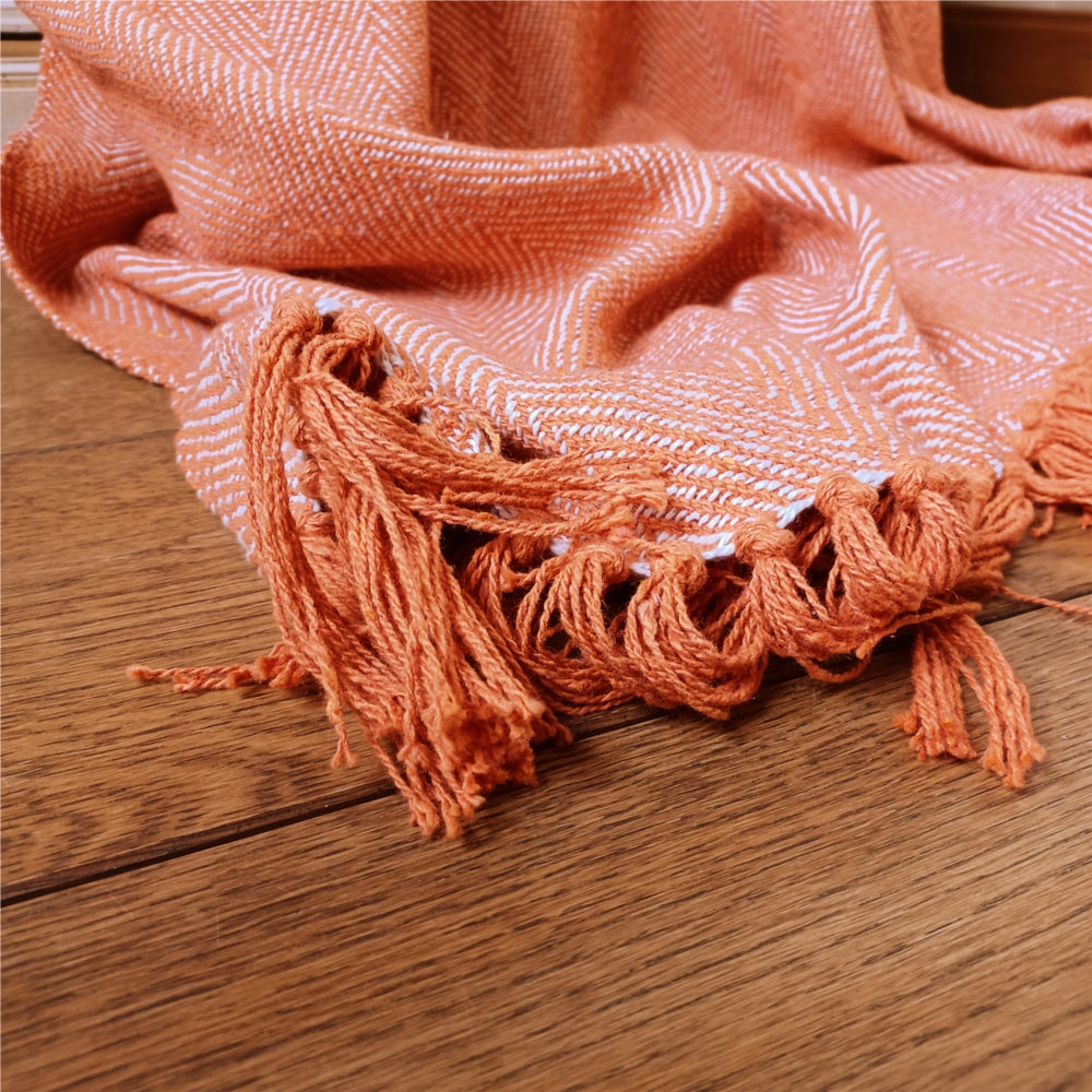 Fiskbensmönstrad pläd i varm orange ton i lantligt inrett vardagsrum