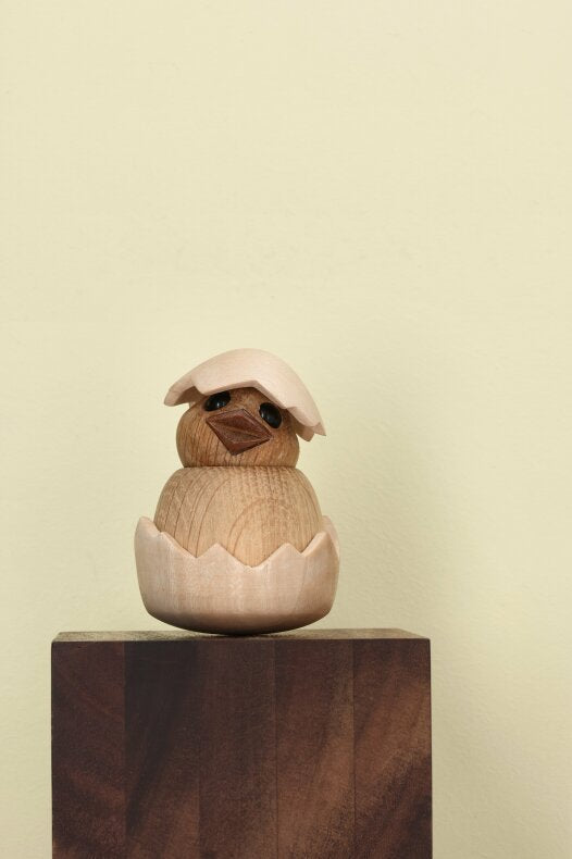 Trädekoration föreställande en kyckling i ek placerad på en rustik träkloss