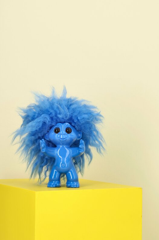 Litet blått lyckotroll placerat på gul yta som nostalgisk inredningsdetalj i sommarstugan