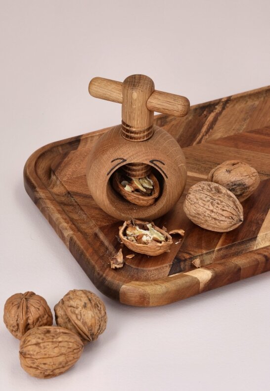 Nötknäckare i trä som krossar valnötter på en rustik serveringsbricka