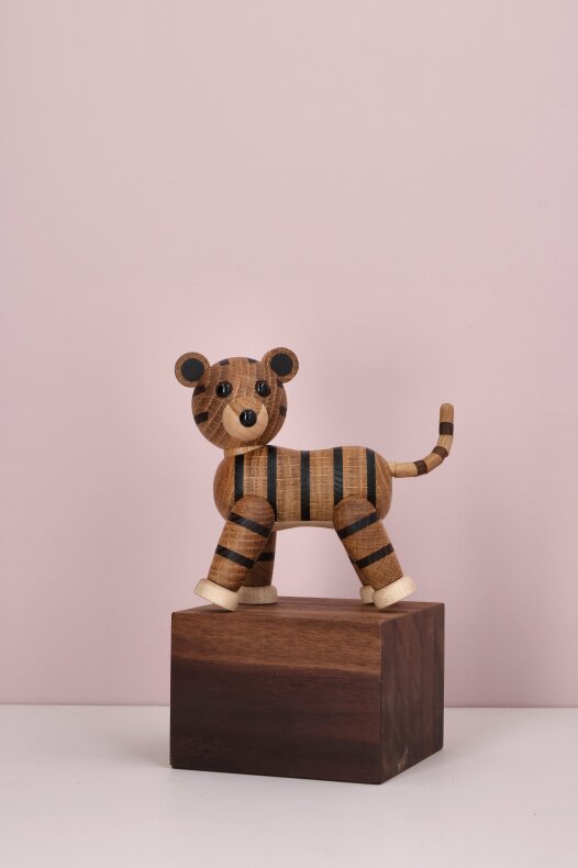 Tigerfigur i FSC-certifierat trä placerad på en mörk träkub