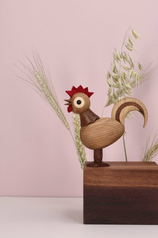 Rise trädekoration placerad på mörkt träblock med torkade ax i bakgrunden