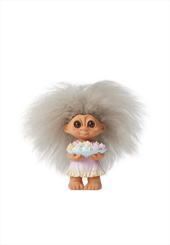 Lyckotroll Sprinkles med grått hår och rosa klänning bärande på ett fat med maränger