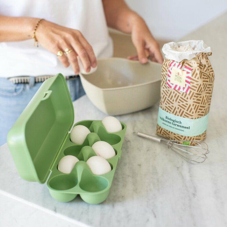 Öppen grön äggbox med vita ägg på köksbänk i ett lantligt kök