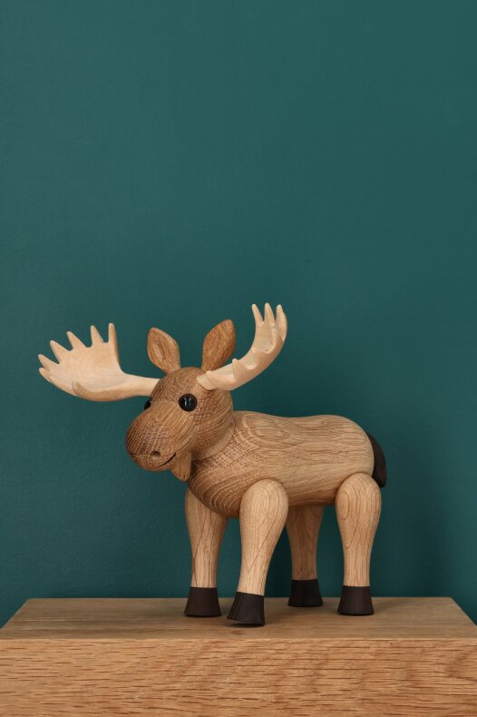 Träfiguren Harald älg placerad på en ekhylla mot mörkgrön vägg