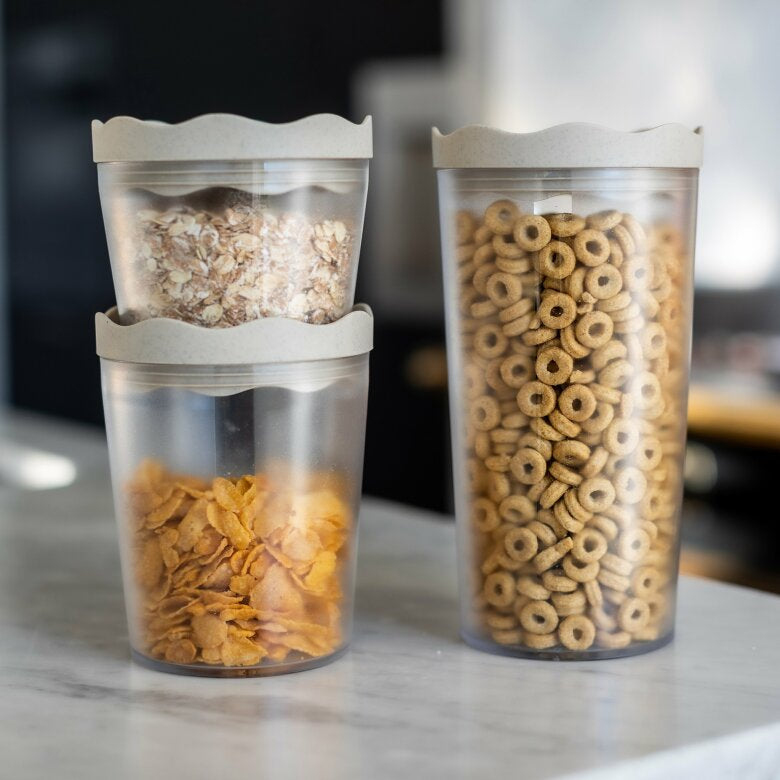 Lufttäta burkar fyllda med flingor och müsli på en köksbänk i marmor