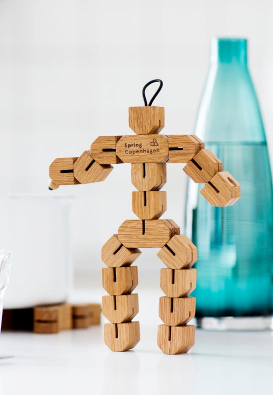 Lekfullt grytunderlägg i ek i upprätt position på köksbänk