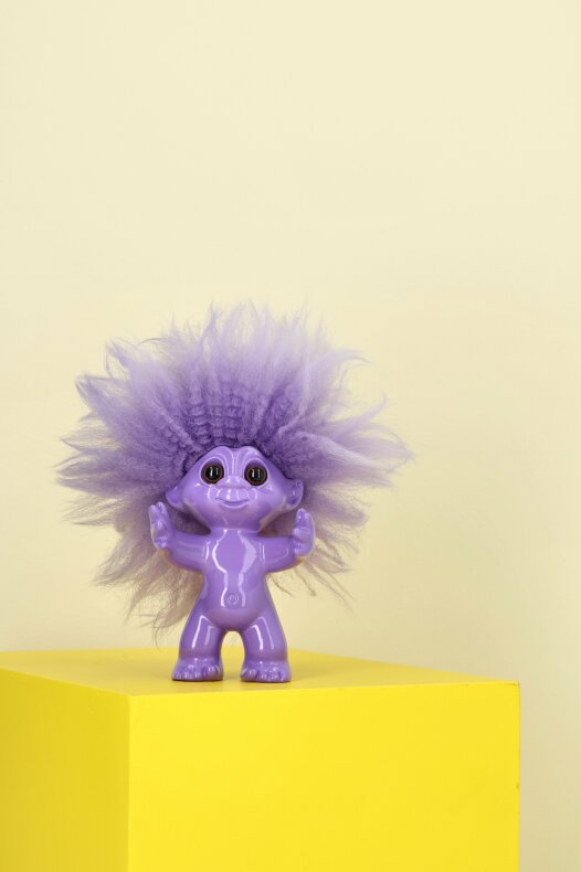 Lila lyckotroll på gul bakgrund som sprider glädje i fäbodens fönster