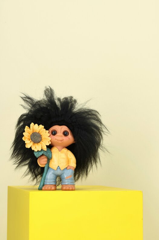 Litet lyckotroll med solros placerat på gul dekor i lantlig miljö