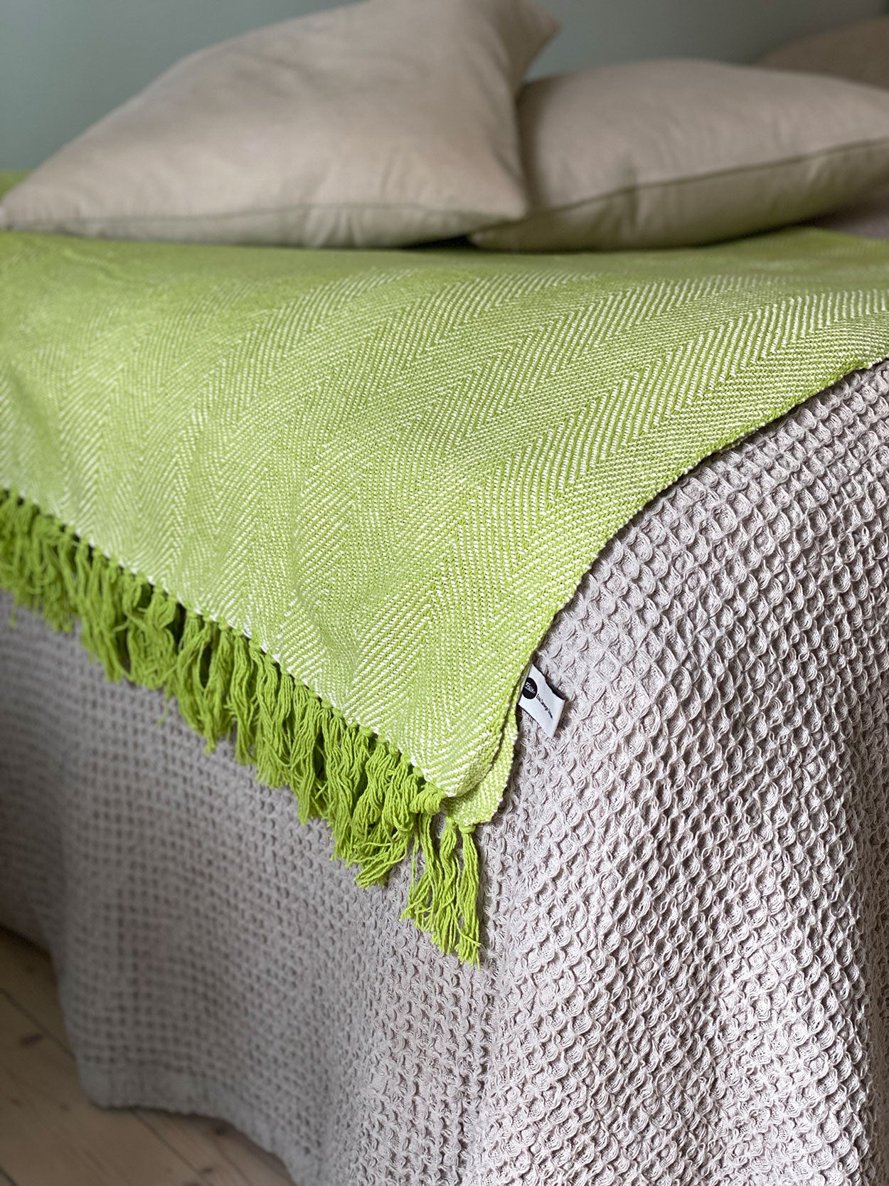 Fiskbensmönstrad pläd i ljusgrön ton i lantligt inrett sovrum eller sommarhus