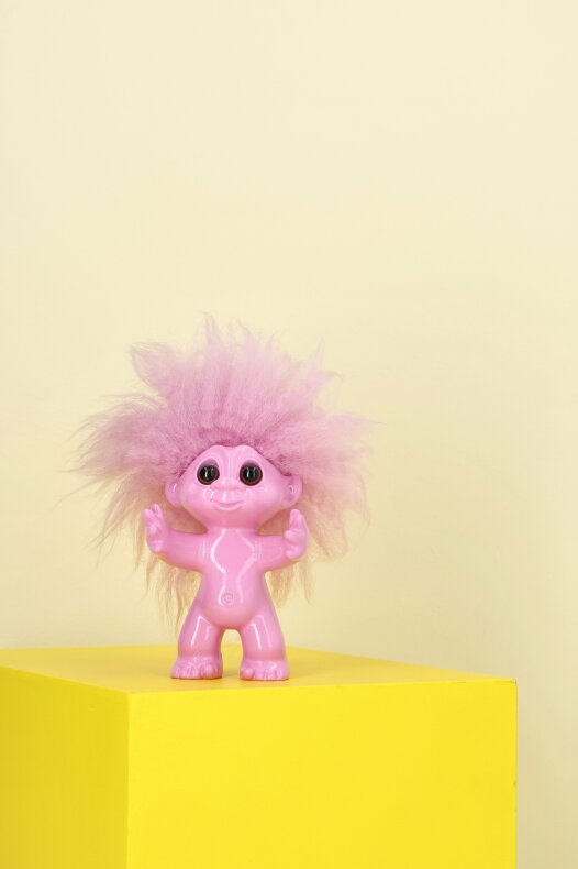 Litet rosa lyckotroll placerat på gul yta i ett ljust lanthem