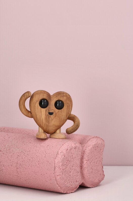 Liten hjärtformad trädekoration i FSC-ek på rosa bakgrund