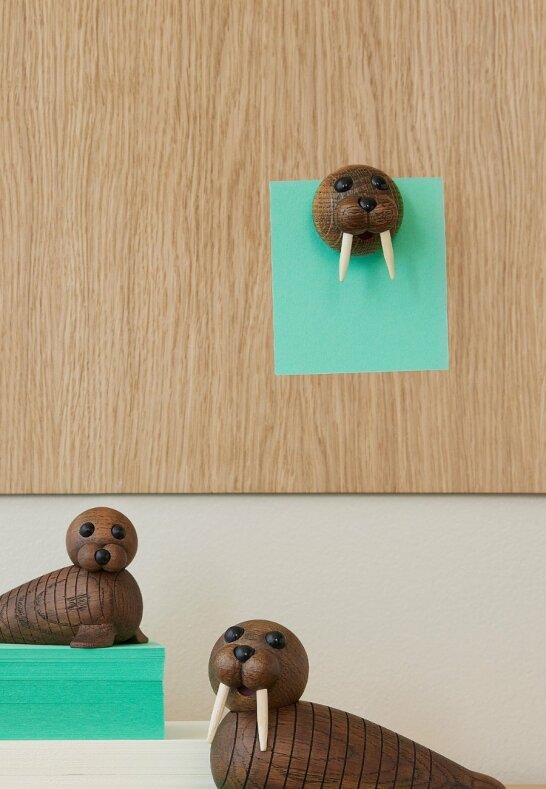 Magnetisk valross i trä som håller ett grönt papper på en anslagstavla